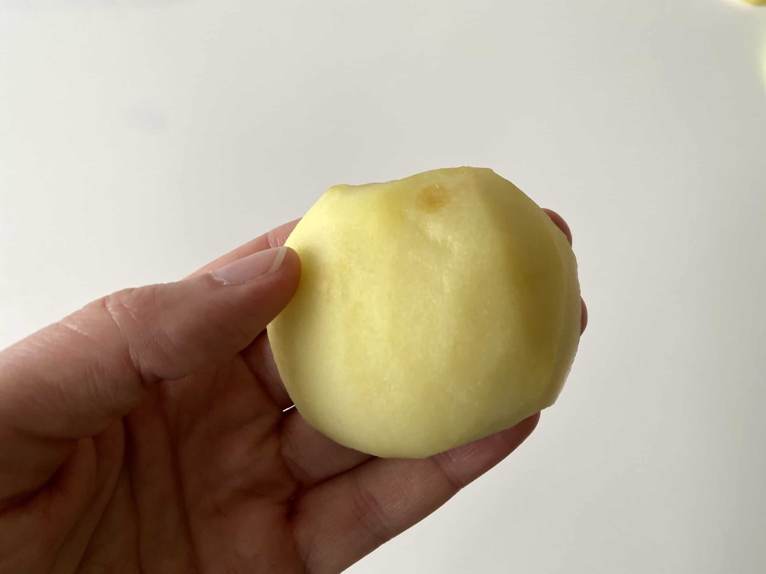 A cooked apple half held in a hand