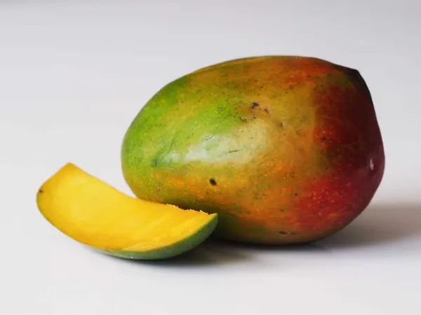 a mango with a piece cut away on a table before being prepared for babies starting solid food