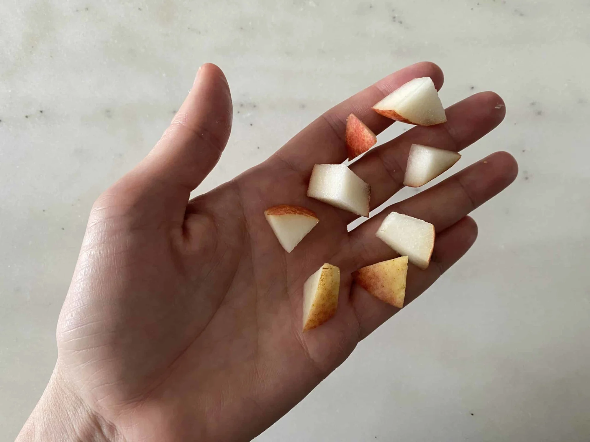 hand holding eight bite size pieces of pear