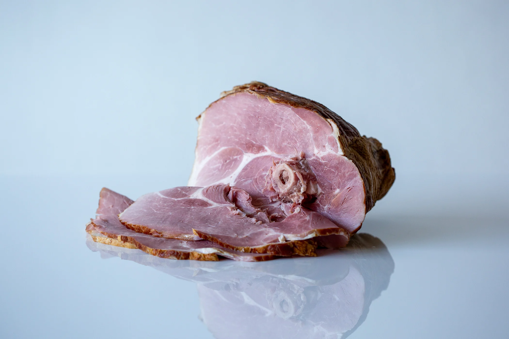 a photograph of a whole cooked spiral cut ham with a few slices cut from it
