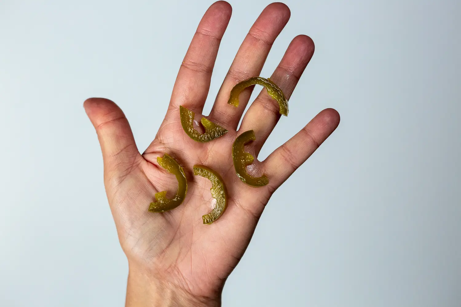 a hand holding five thin strips of jalapeno pepper for toddlers 12 months+