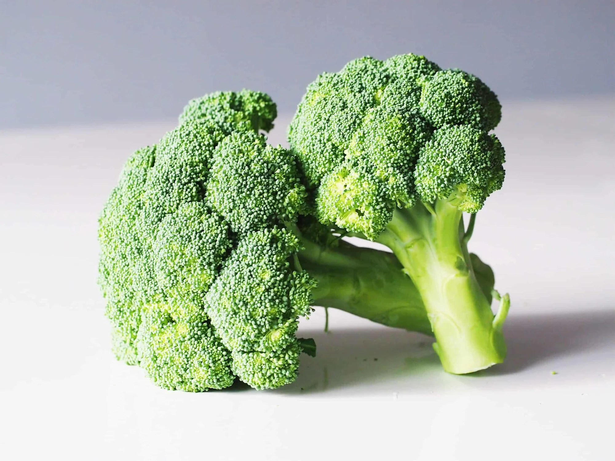 ¿Cuándo pueden comer brócoli los(as) bebés? two heads of broccoli on a table before being steamed for babies starting solids