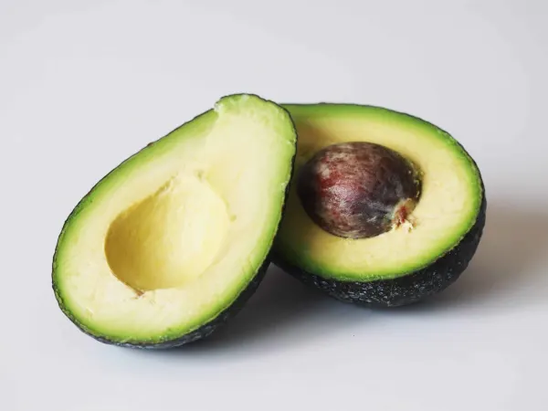 An avocado sliced in half getting prepared for a baby starting solid foods