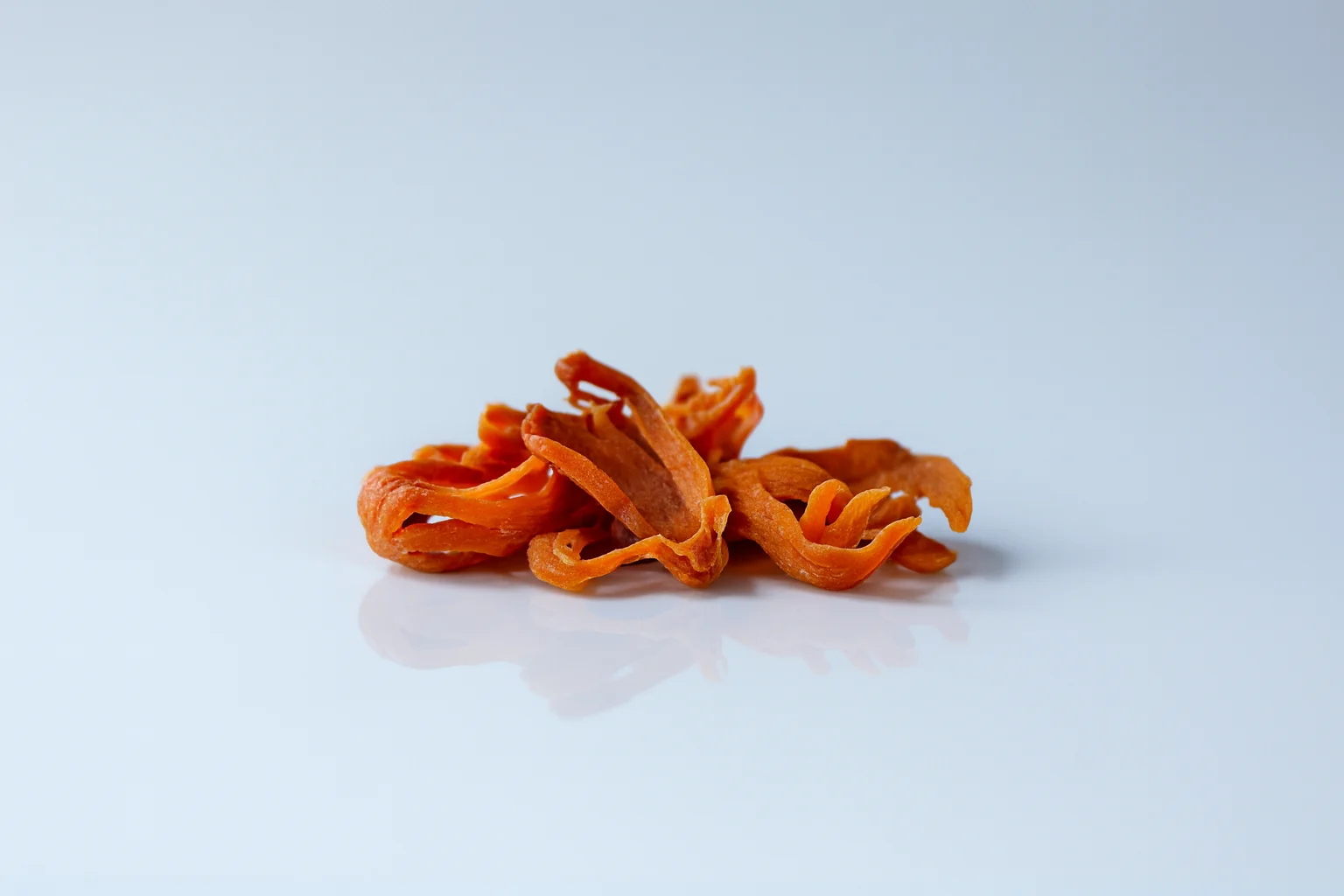a photograph of a few whole blades of mace on a white background