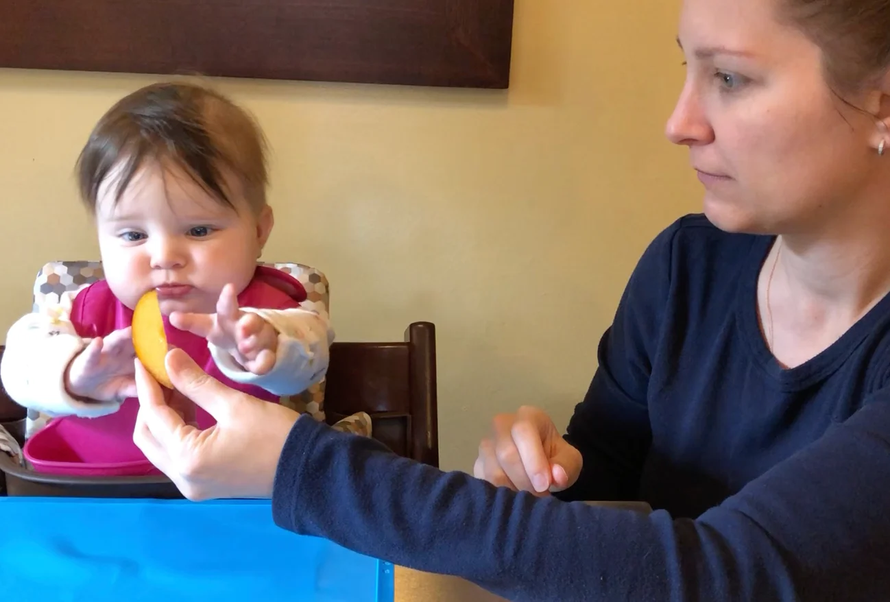 Kim hands Maeve, 6 mos, a slice of peach