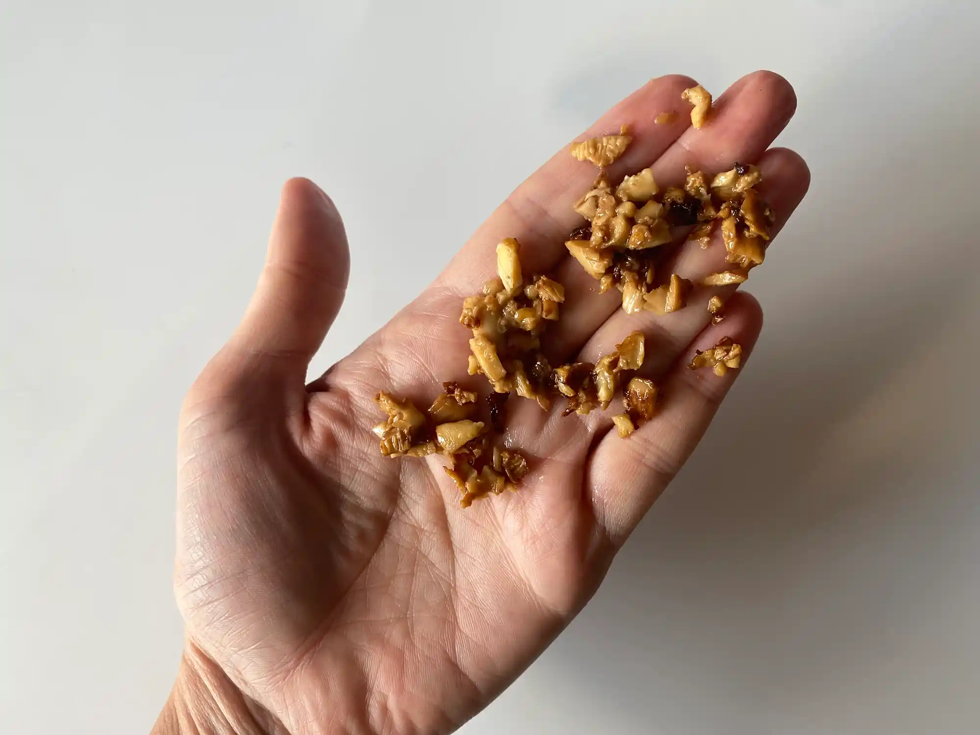 a hand holding a small pile of finely chopped chanterelle mushroom