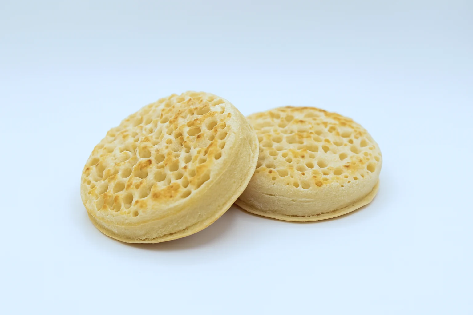 a photograph of two toasted crumpets on a white background