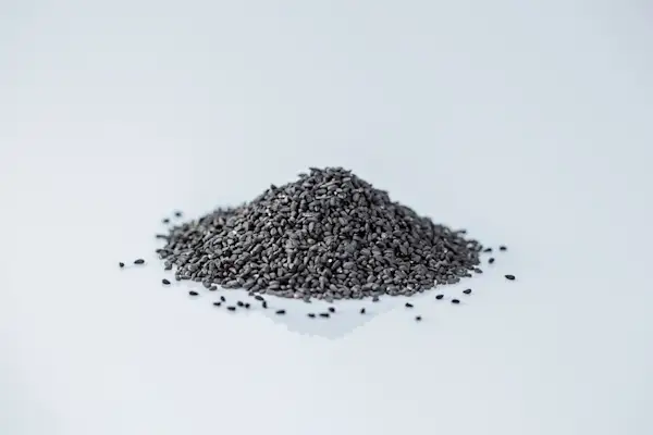 a photograph of a small pile of nigella seeds on a white background
