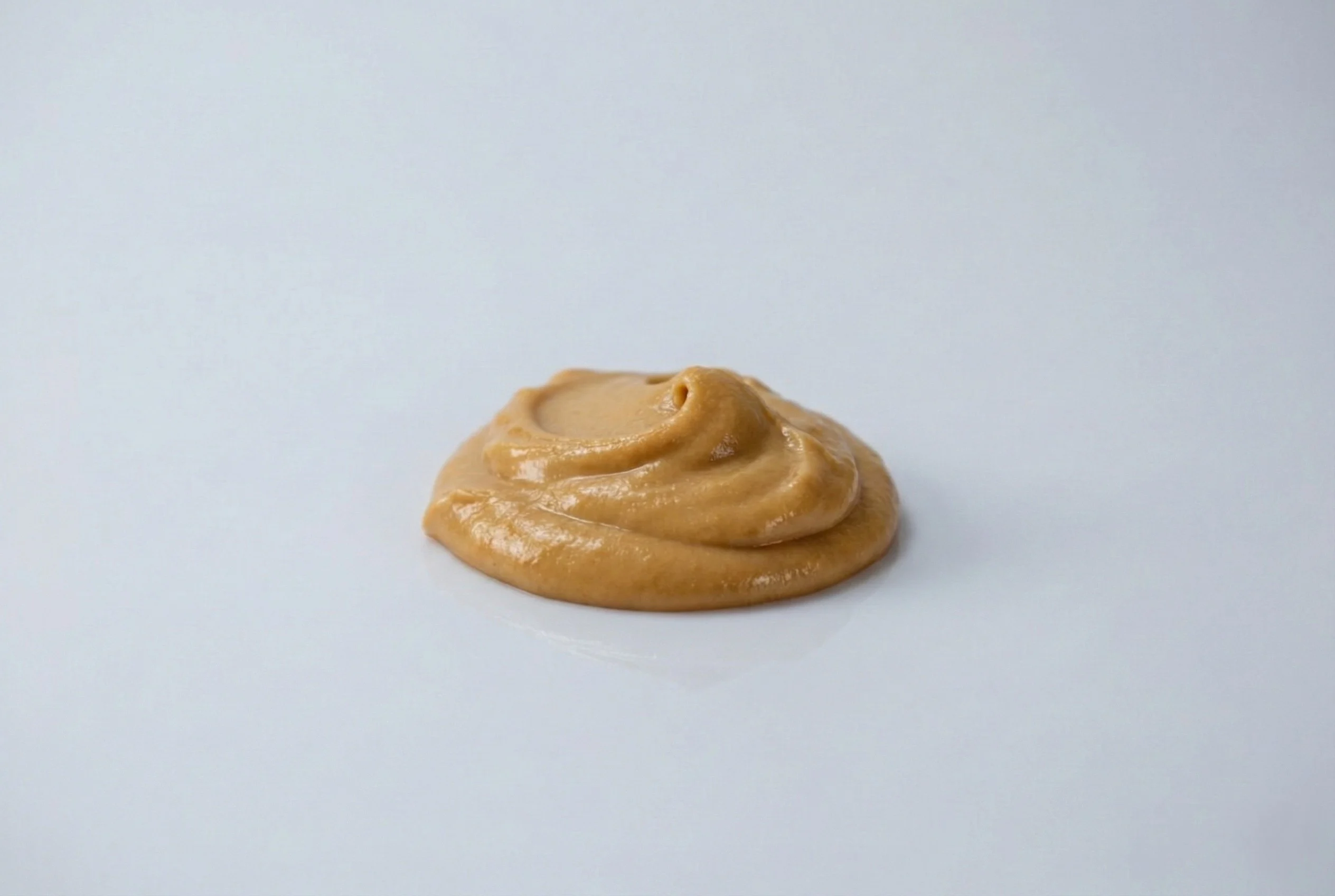 a photograph of a blob of smooth peanut butter on a white background