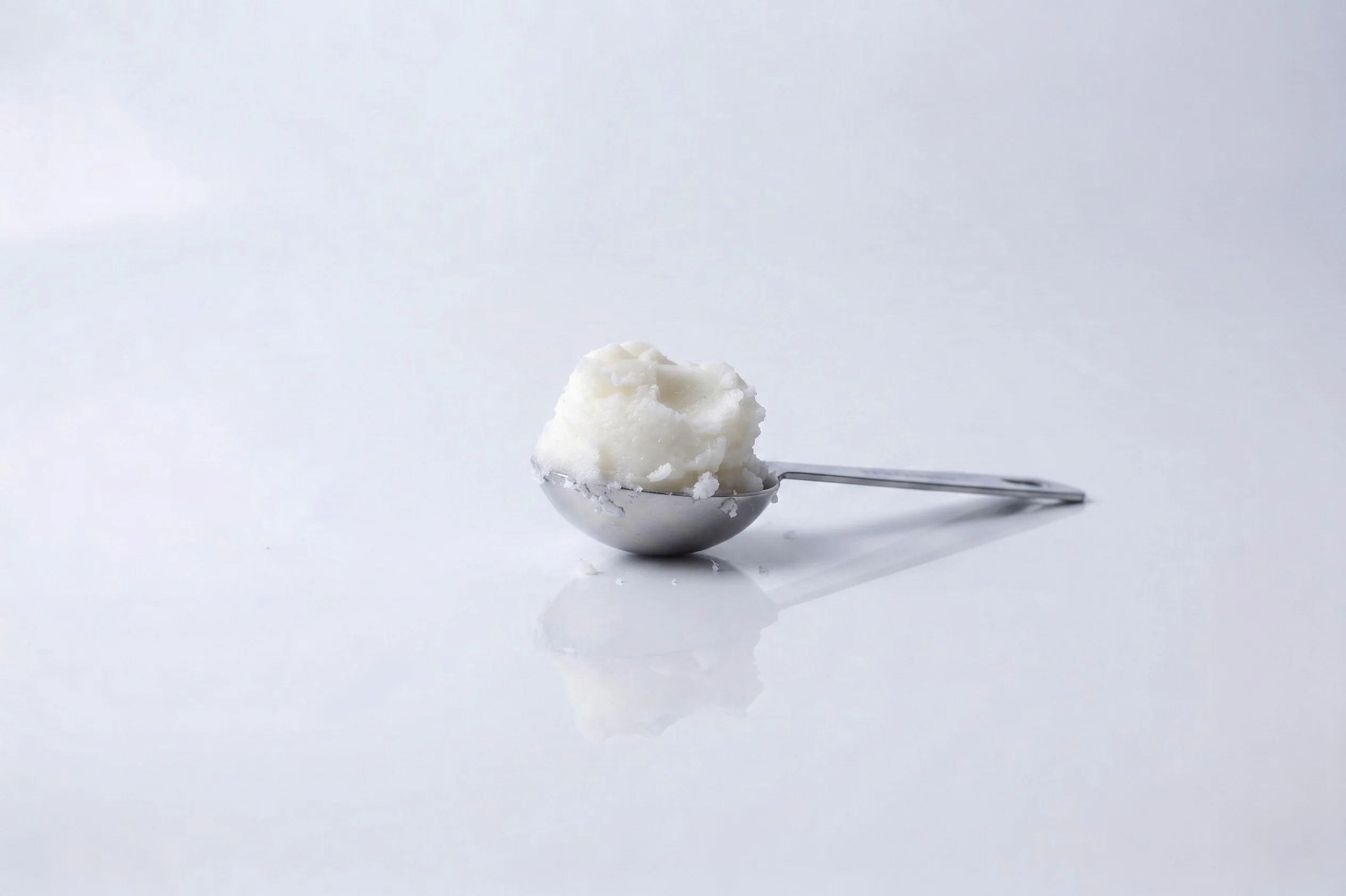 a photograph of a tablespoon filled with manteca on a white background