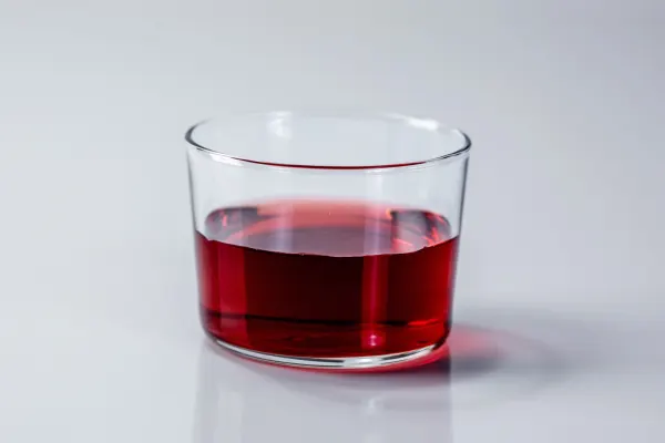 a clear glass half full of red juice