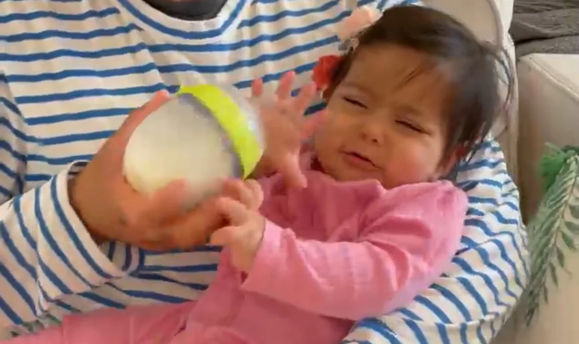 a photograph of a baby being held and offered a bottle, but the baby is crying and pushing the bottle away