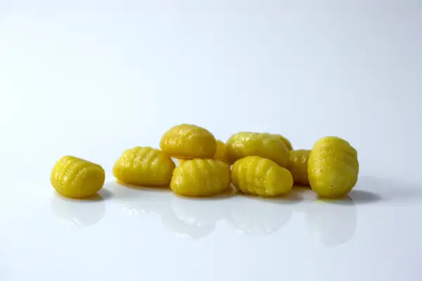 ten whole cooked gnocchi on a white background