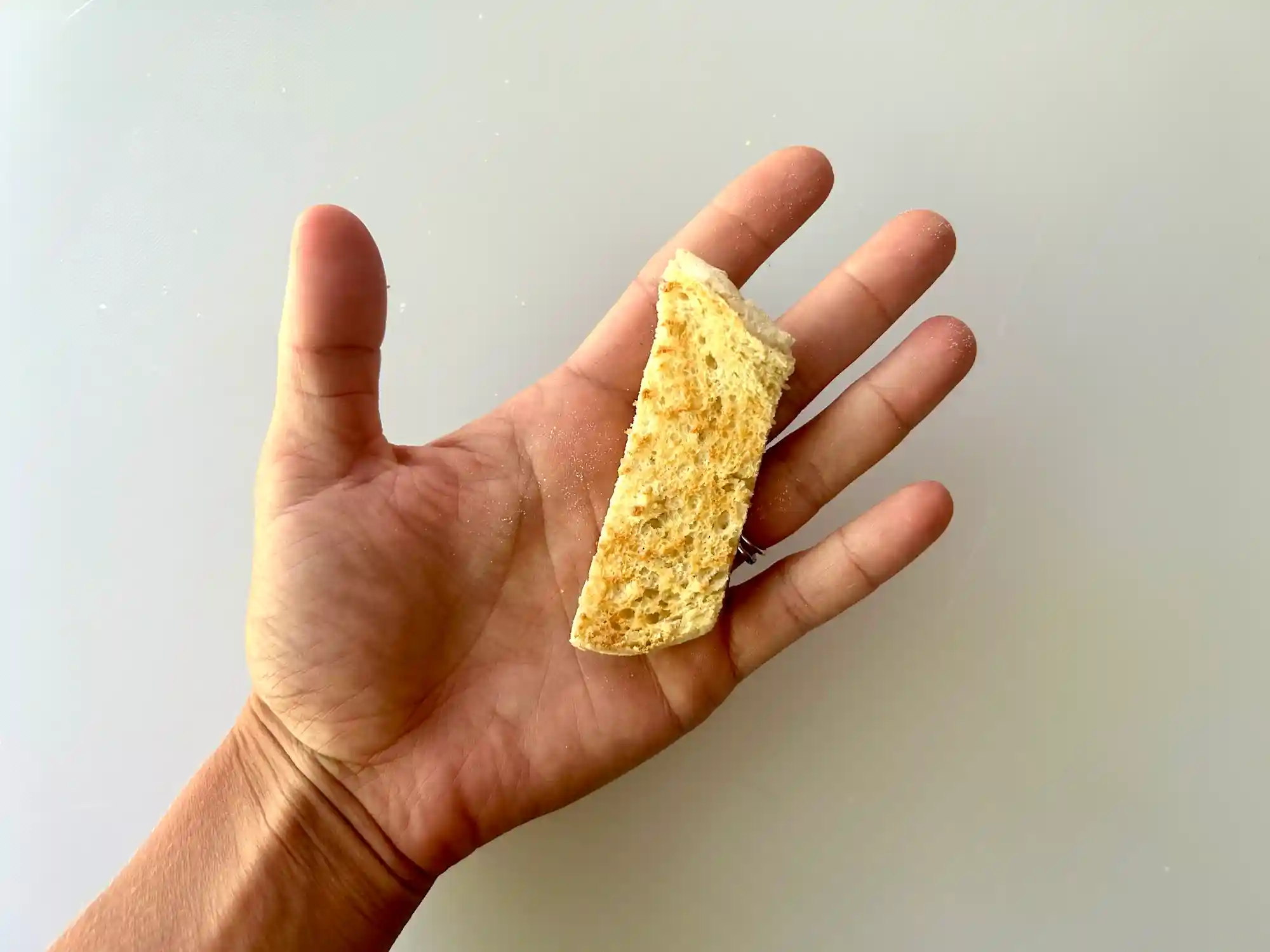 English muffin strip hand pic a photograph of a hand holding a toasted strip of english muffin