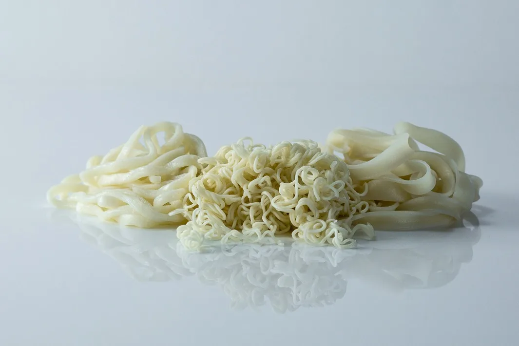 three piles of cooked noodles on a white background