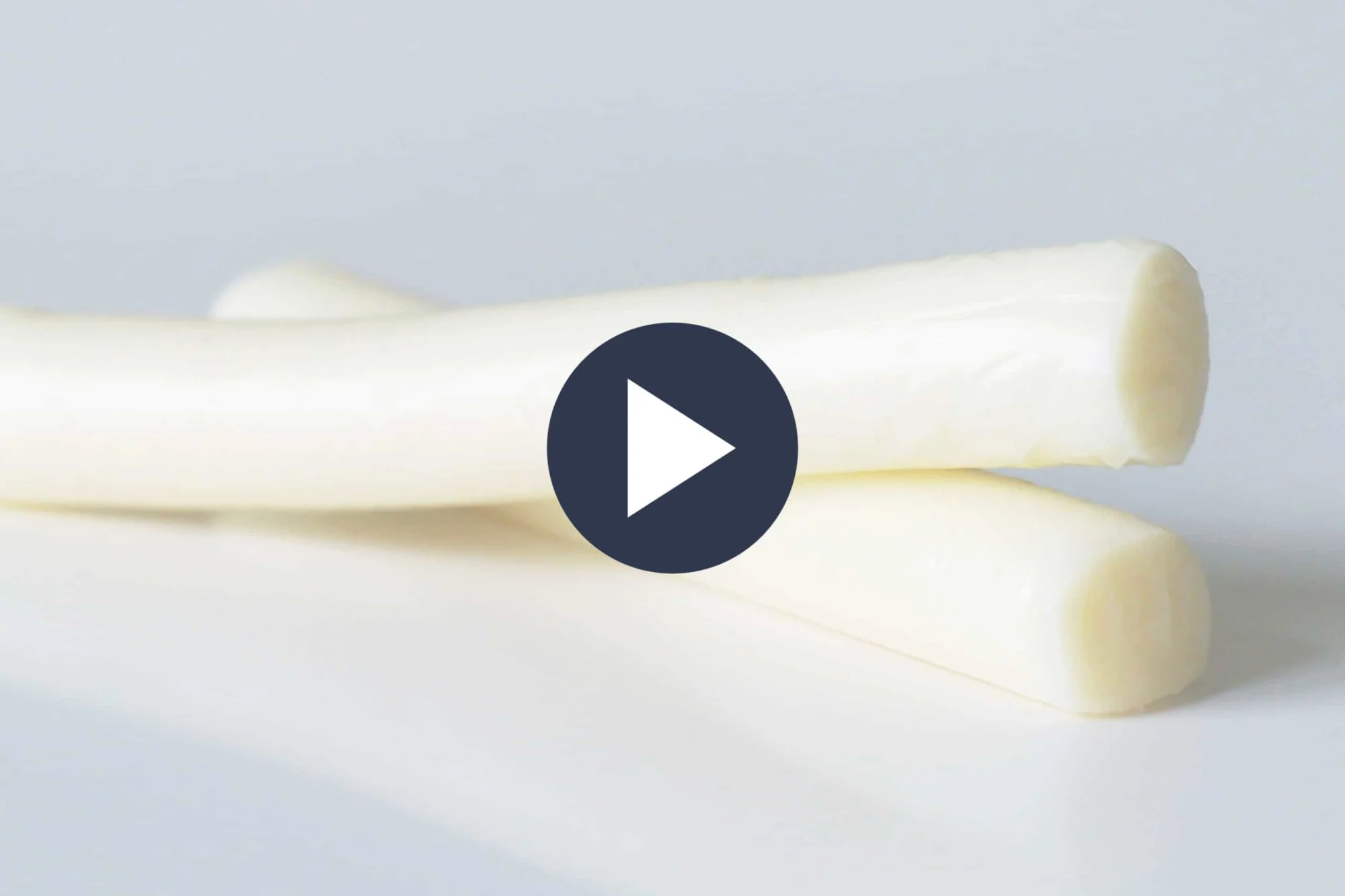 two white string cheese one on top of the other over a white table and background