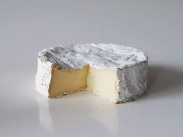 a wheel of camembert cheese with a wedge cut out of it
