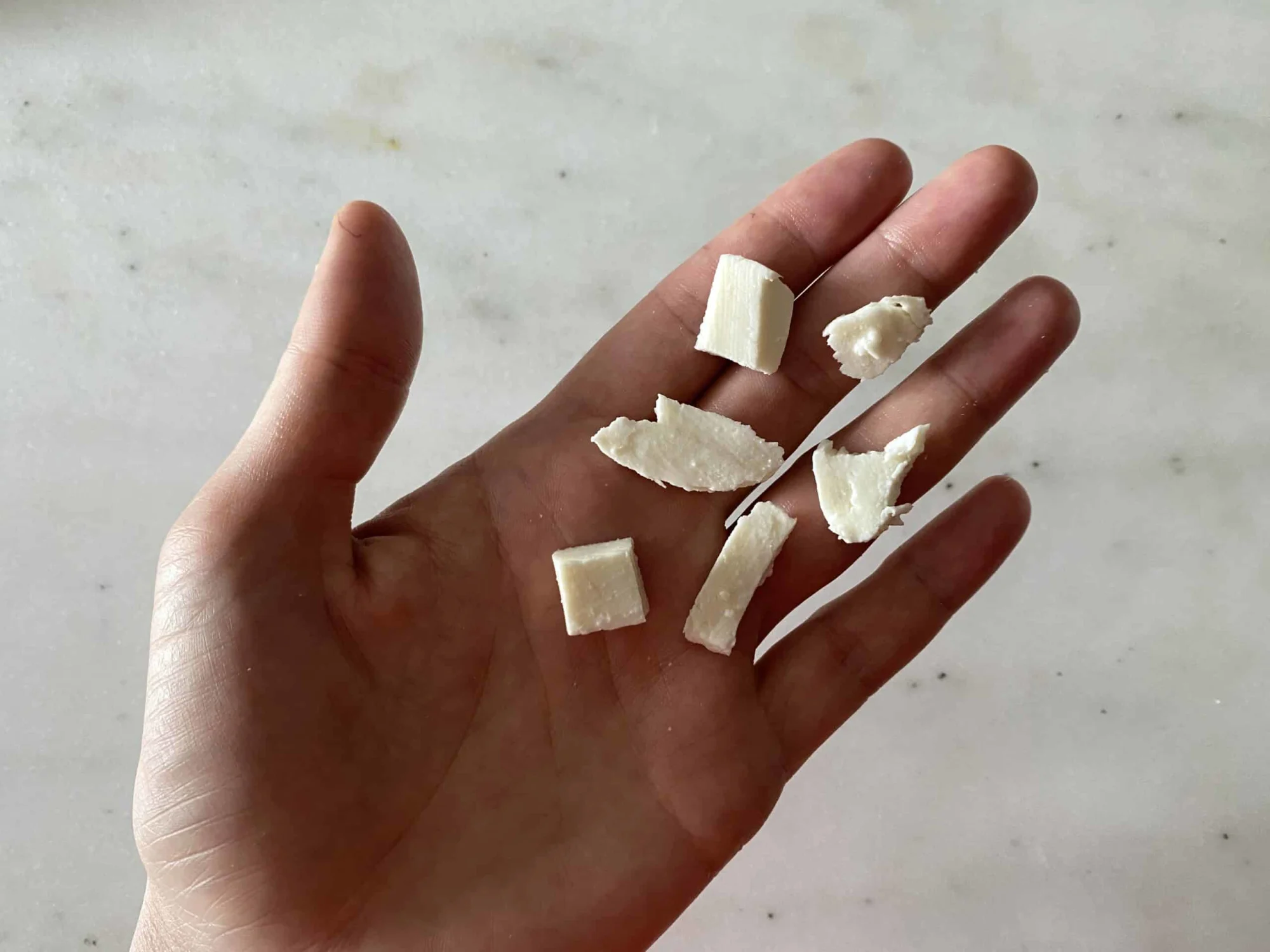 hand holding several bite sized pieces of mozzarella cheese