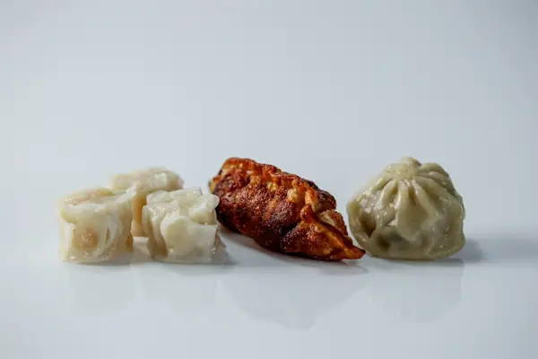 a photograph of three different kinds of cooked dumplings on a white background