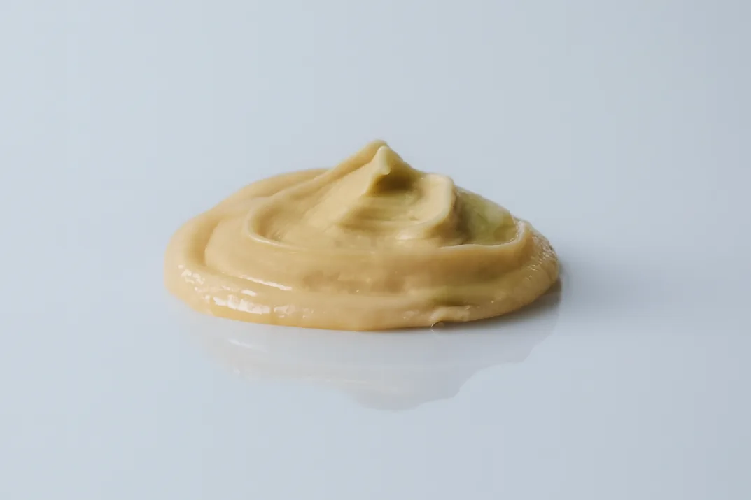 a photograph of a small pile of smooth cashew butter on a white background