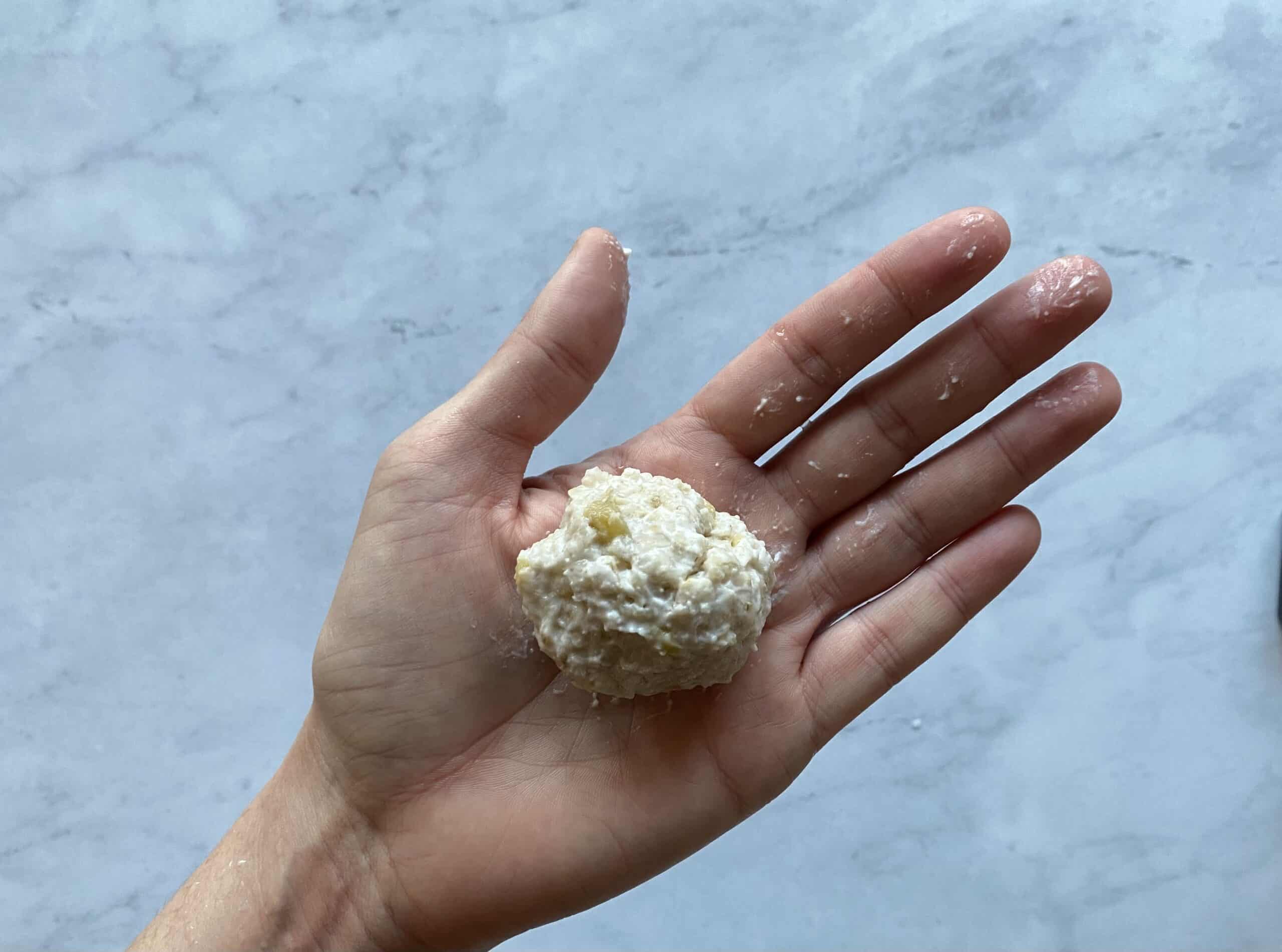 a hand holding some oatmeal pressed into a ball for babies 6 mos+