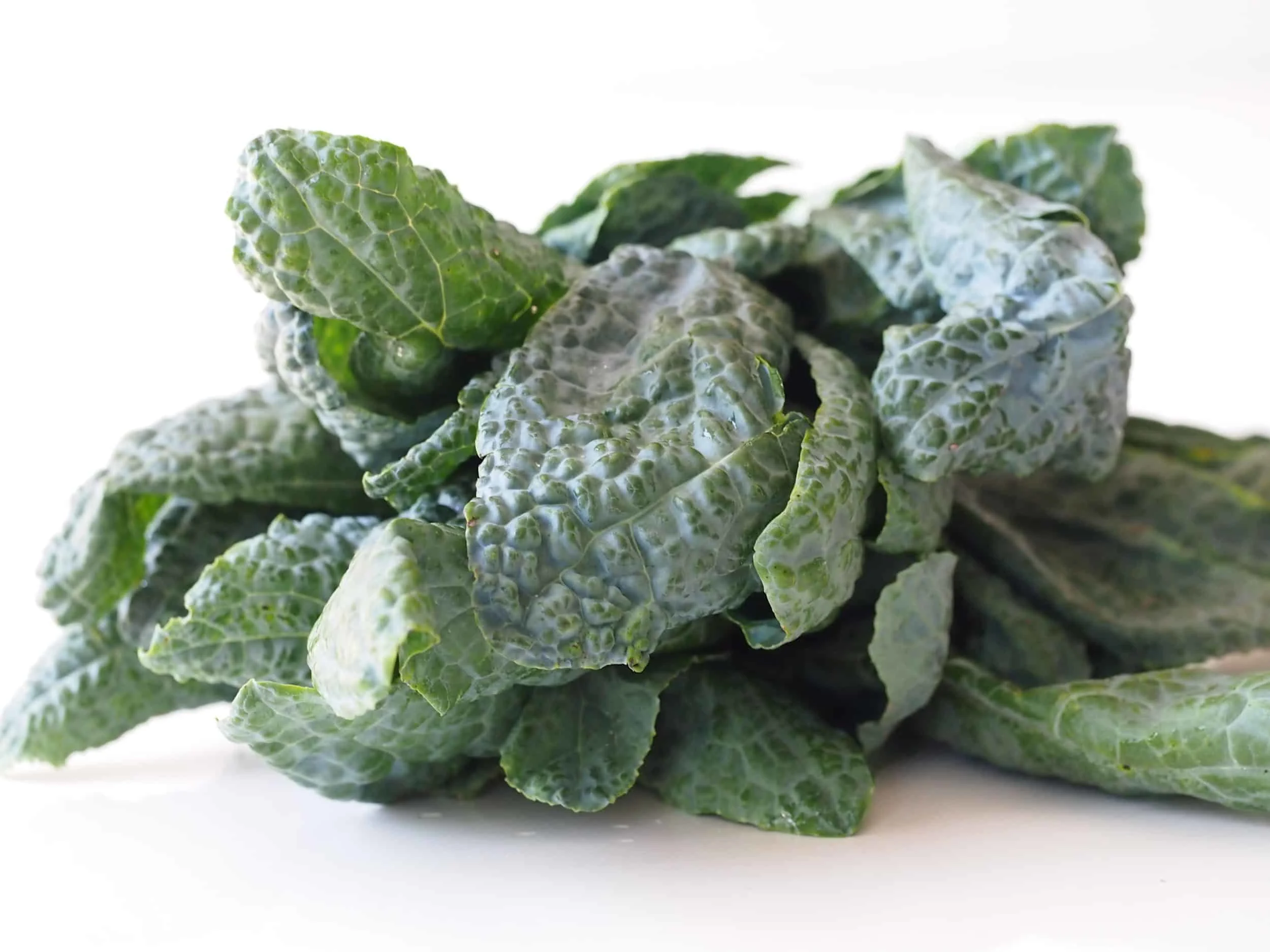 a pile of raw lacinato kale on a white table before being prepared for babies starting solid food