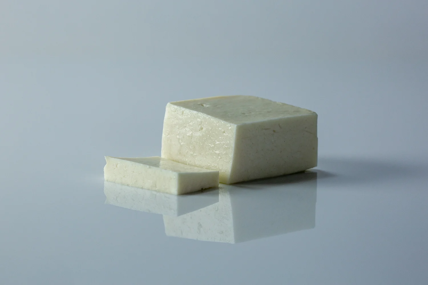 a photograph of a block of halloumi with a slice cut off