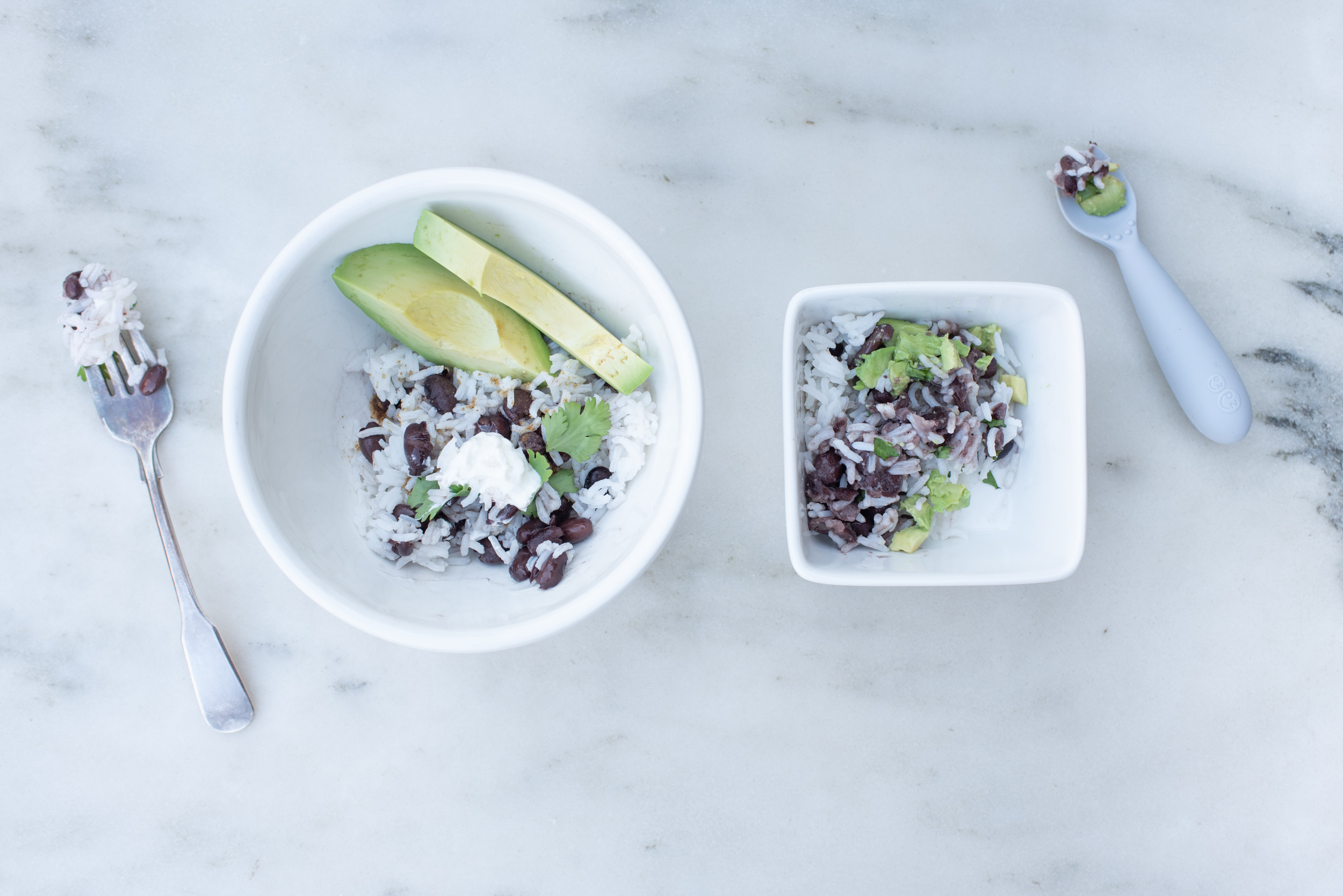 burrito bowl containing beans, rice, and avocado on a white background