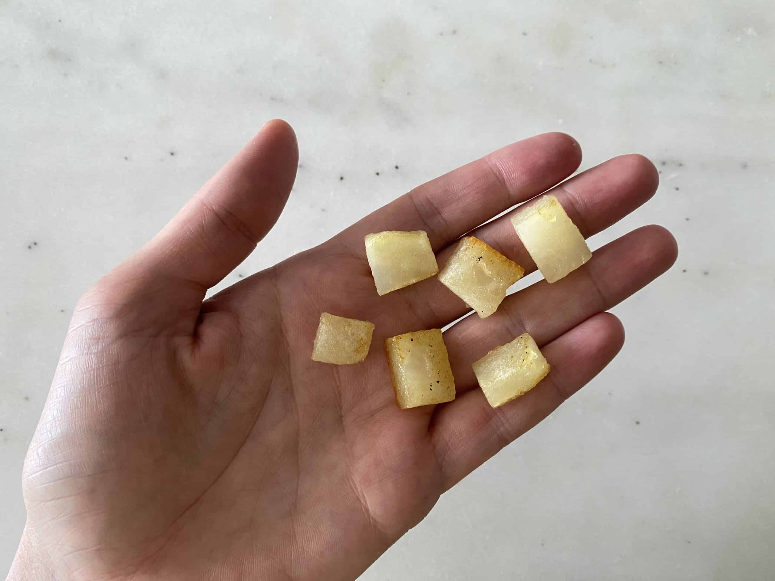 hand holding out six bite sized pieces of white potato