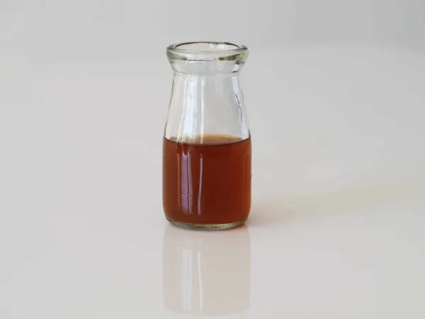 a small glass container filled with bone broth on a plain background
