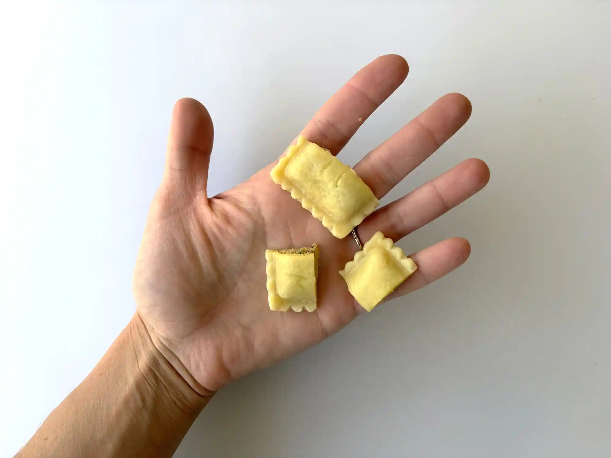 Ravioli bite-sized pieces hand pic a photograph of a hand holding a ravioli cut in half and in quarters