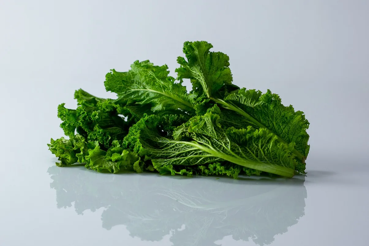a few raw whole mustard greens on a white background