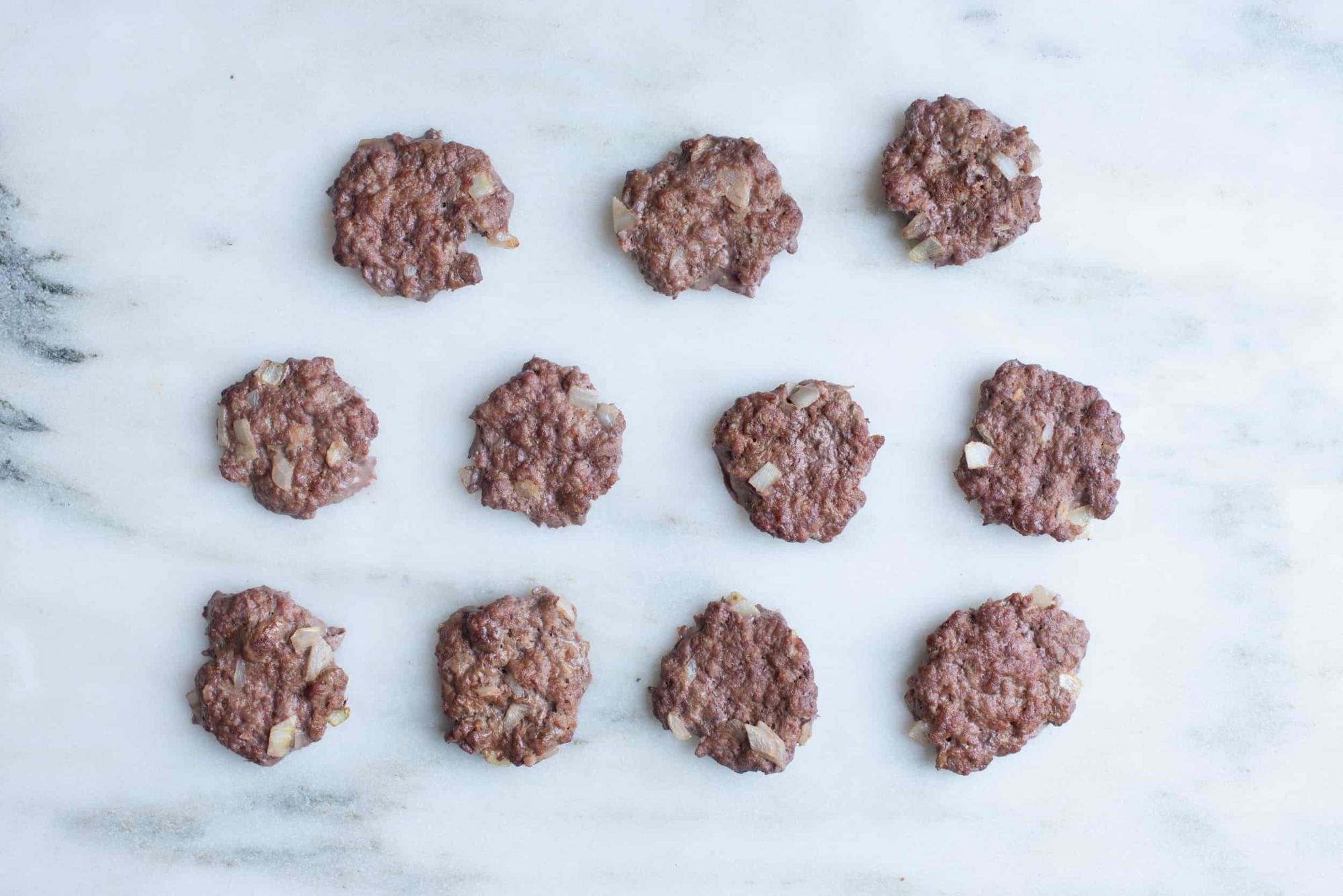 eleven meat patties on a white background