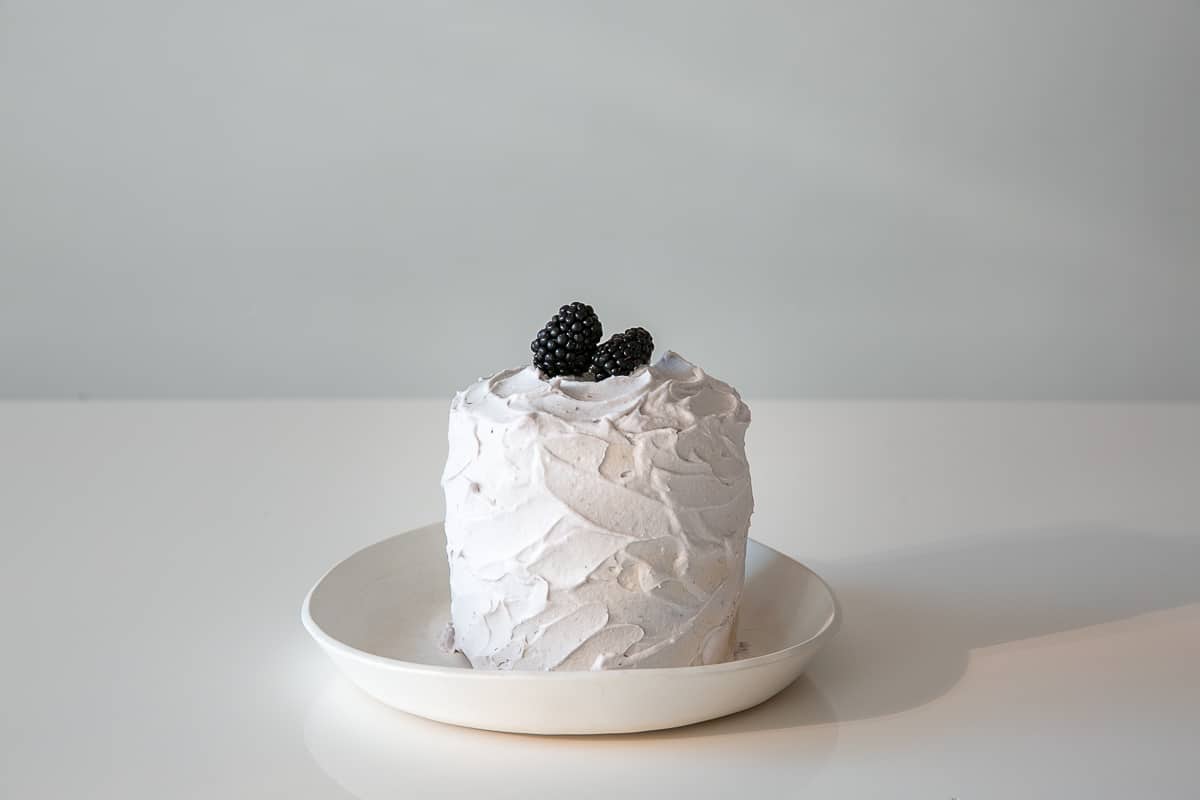 a white smash cake for a baby with blackberries on top