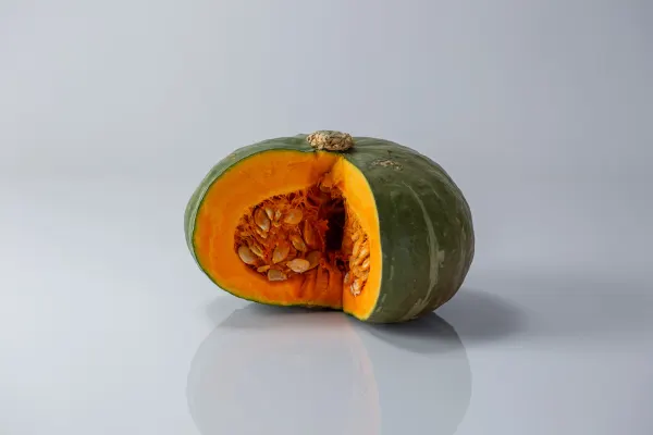 a whole raw kabocha squash with one wedge cut out to show the inside