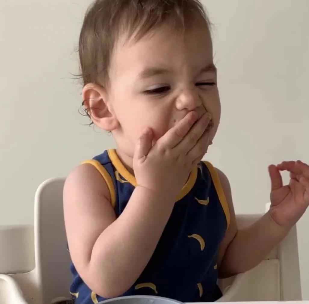 un bebe se embute comida en la boca al iniciar la alimentación complementaria
