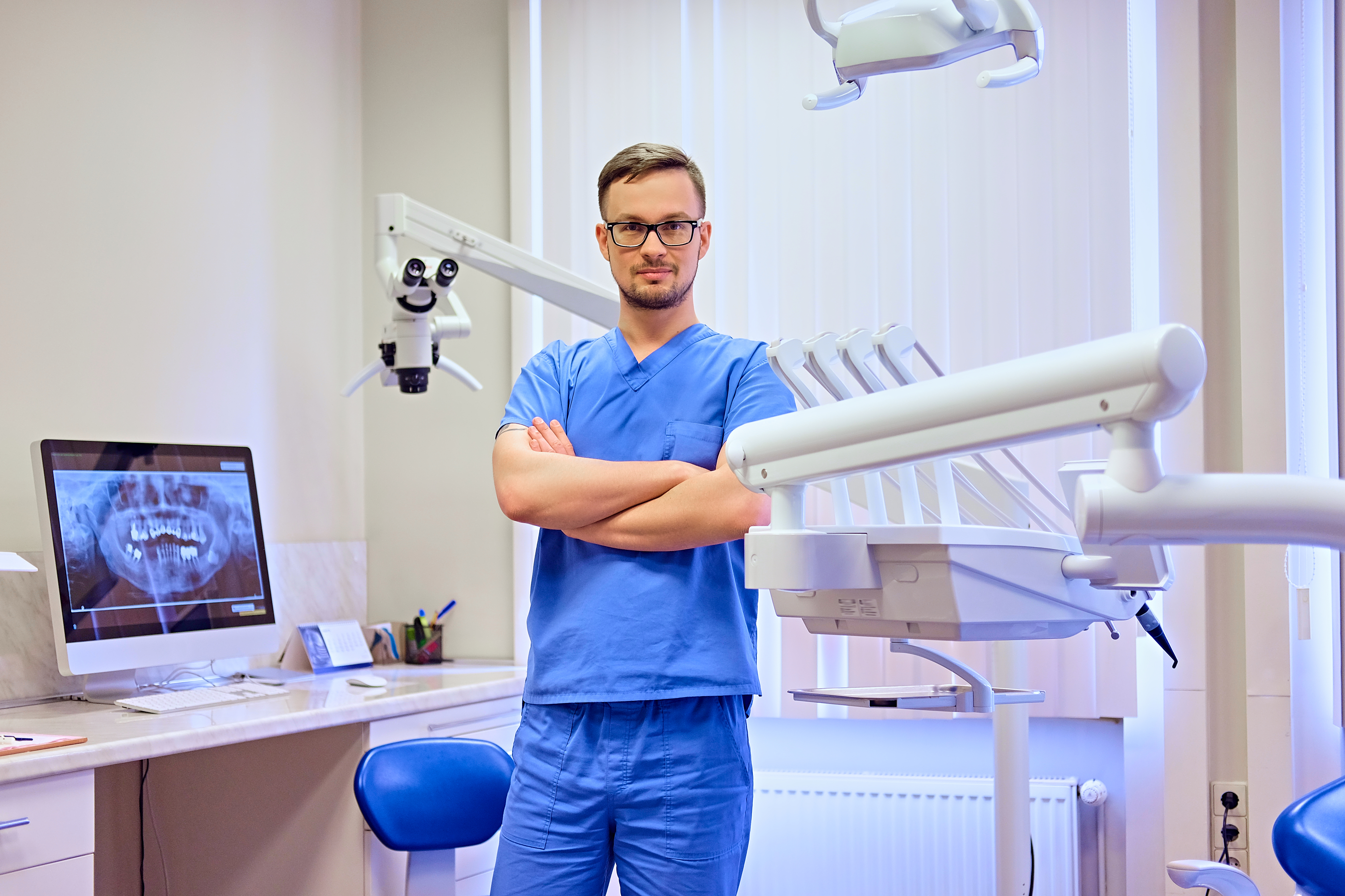 handsome-male-dentist-room-with-medical-equipment-background