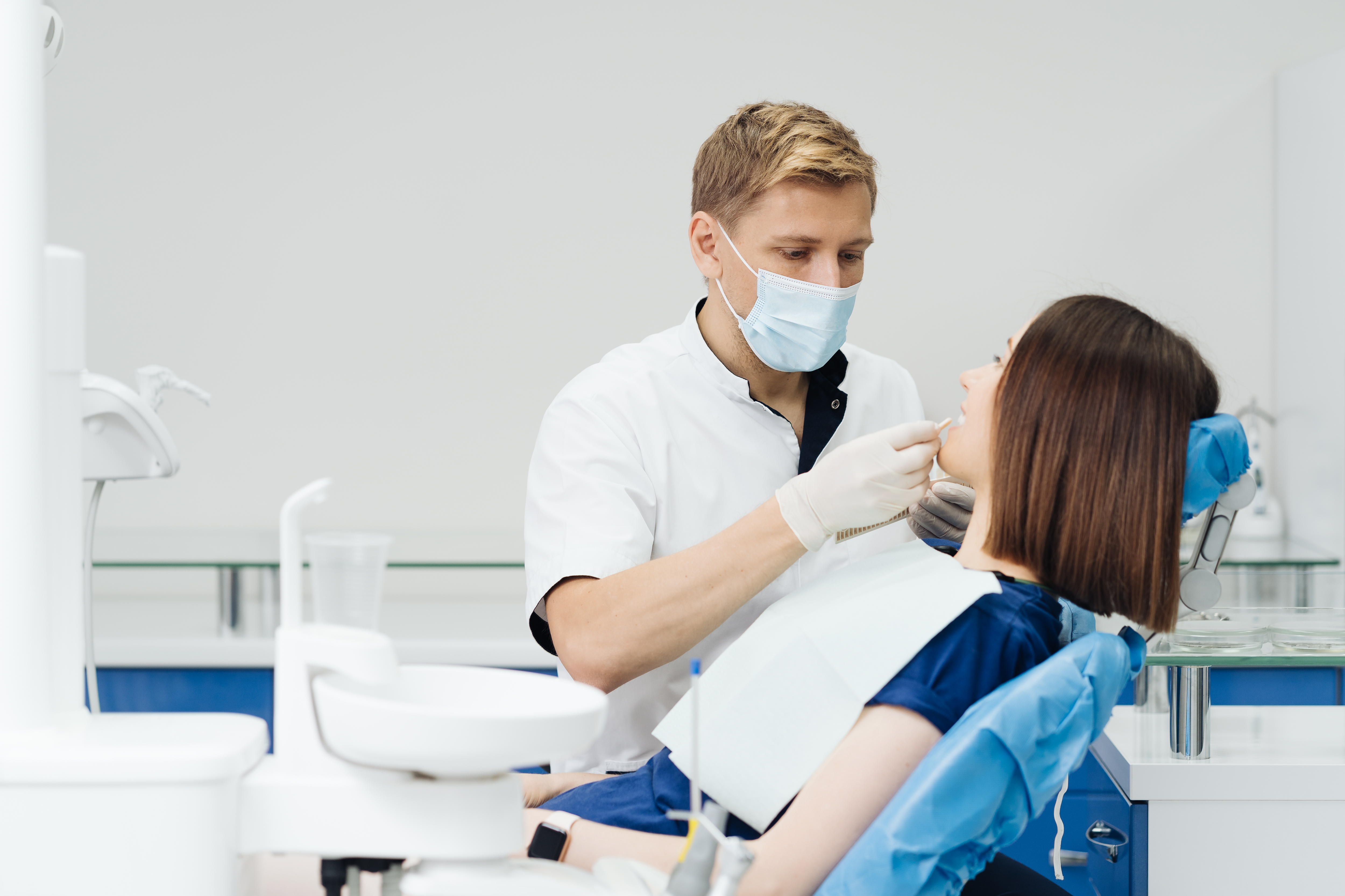 close-up-portrait-beautiful-young-lady-sitting-dental-chair-while-stomatologist-hands-sterile-gloves-holding-tooth-samples