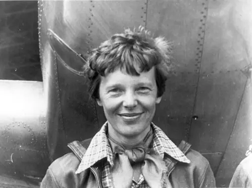 Amelia Earhart standing under nose of her Lockheed Model 10-E Electra, small