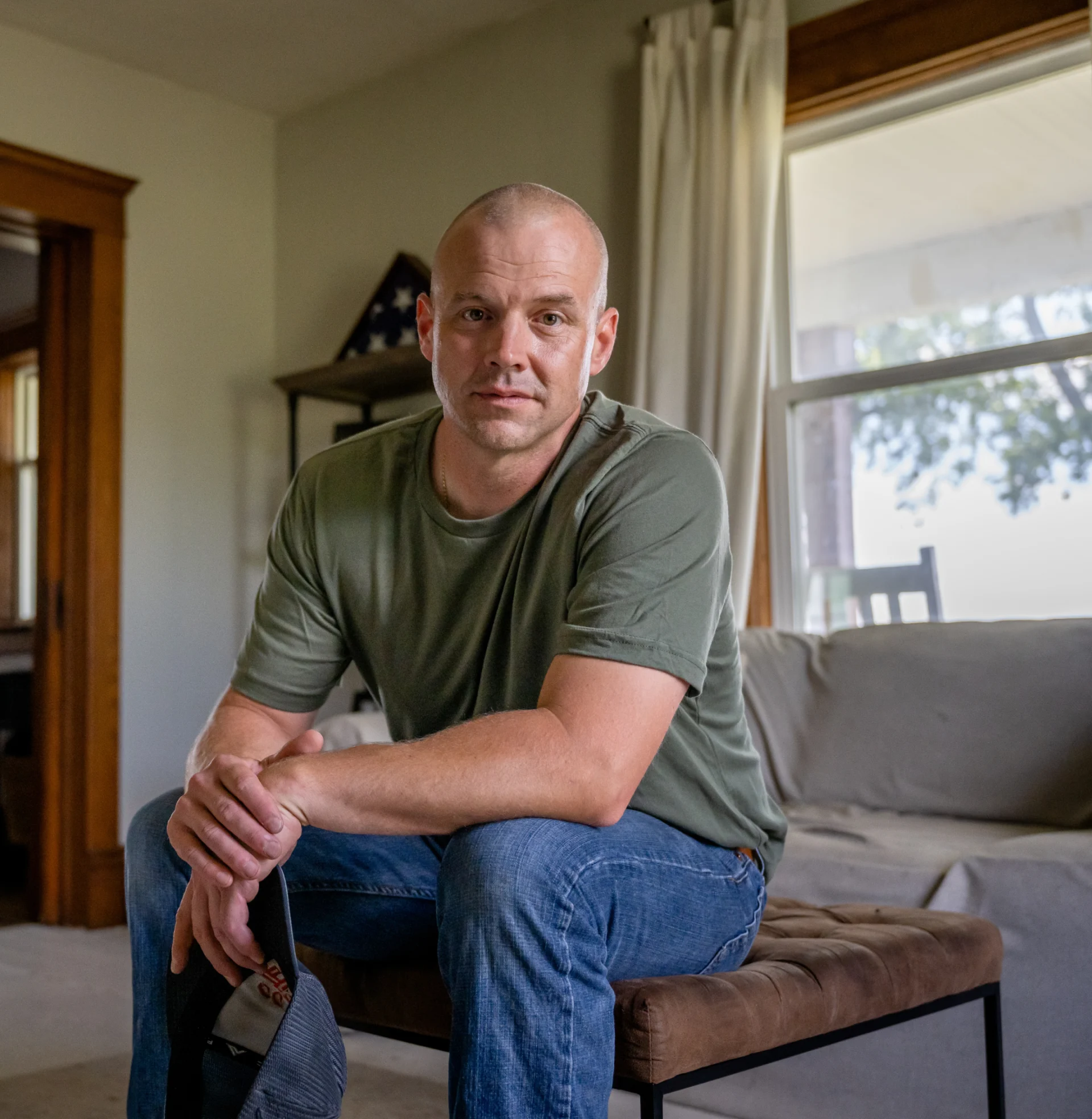 A man sitting pensively in his living room, looking at the camera