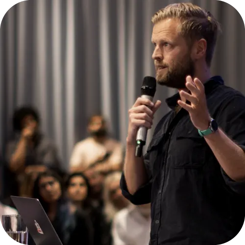 A man speaking in front of an audience with a microphone