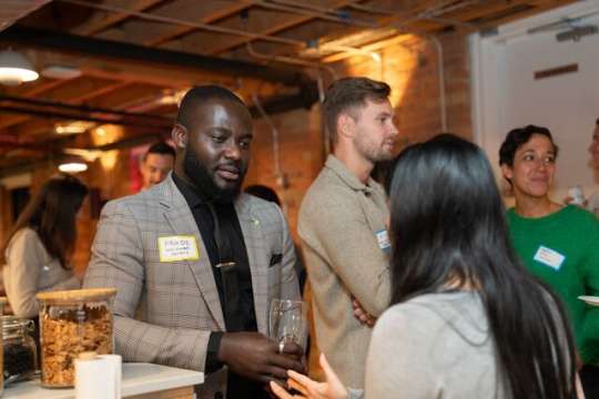 In front a Mentimeter representative engaging in discussion with a woman, other people enjoying themselves in the background