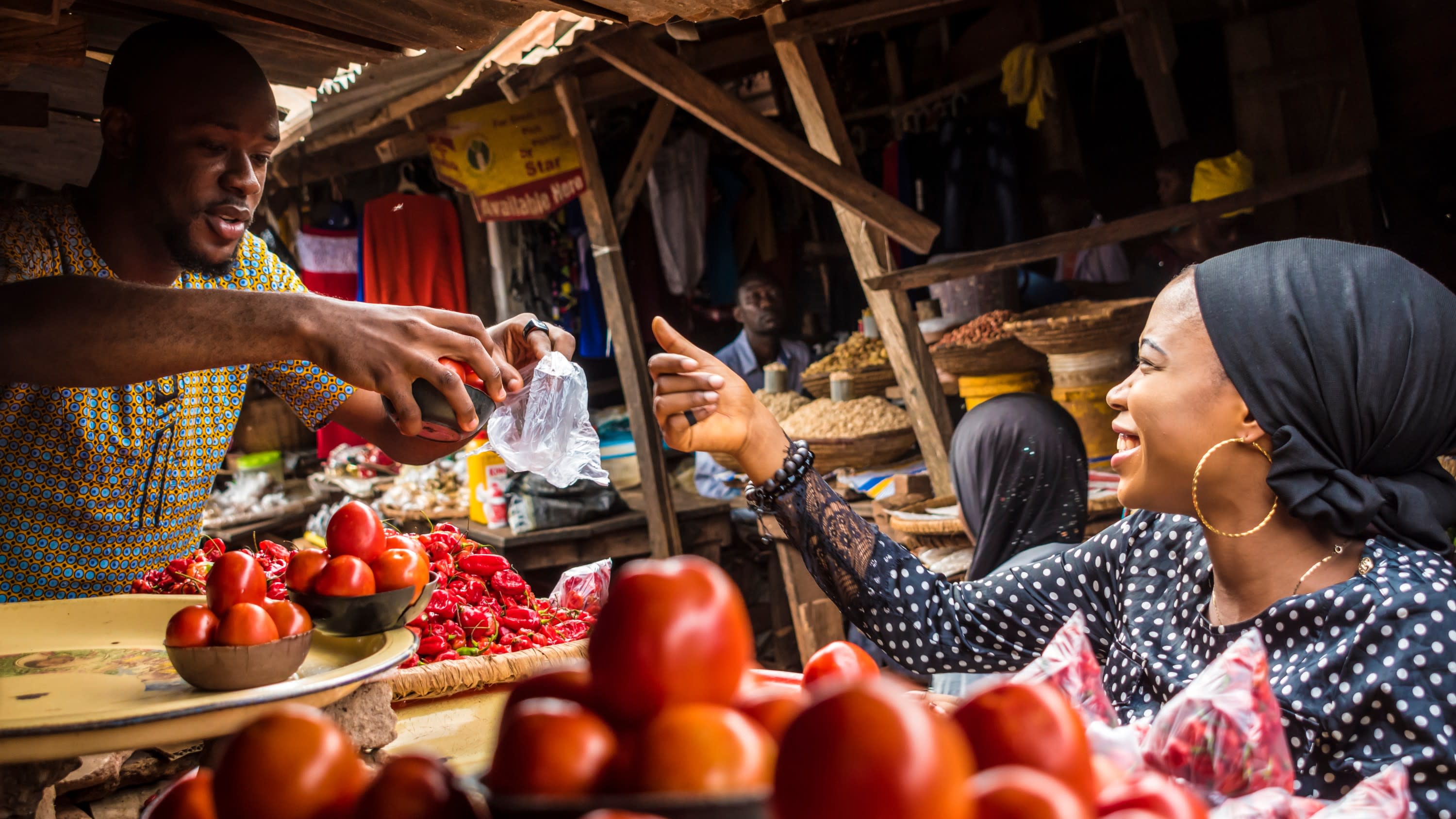 Afrikanische Dame bezahlt an einem Tomatenstand