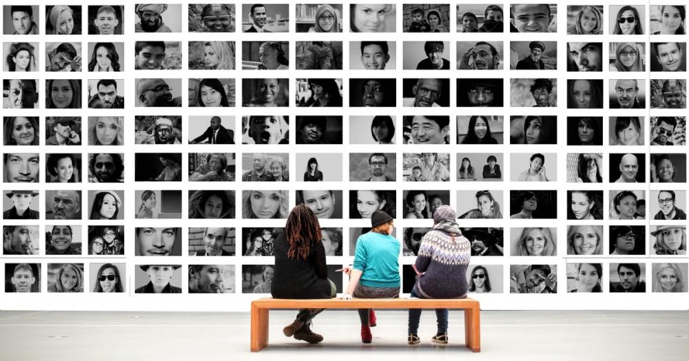 people sit on a bench and look at a collage of black and white portraits