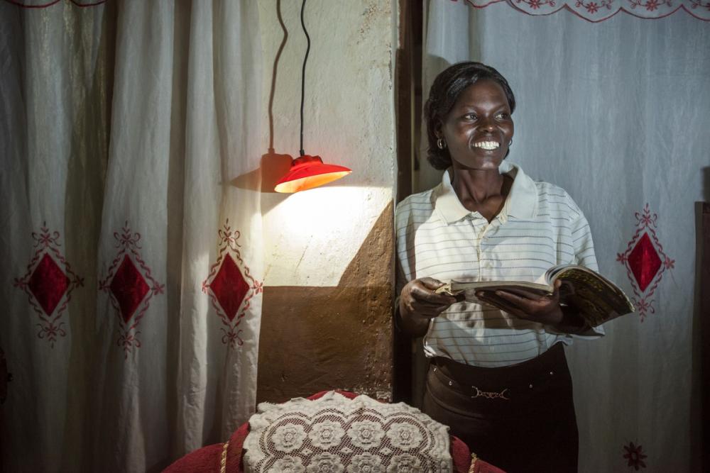 A woman smiles because she has solar-powered electricity