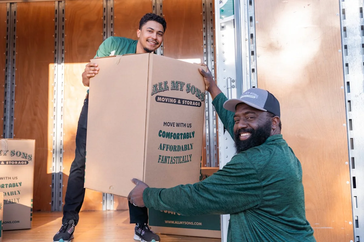 Professional movers from All My Sons load a computer box into a moving truck.