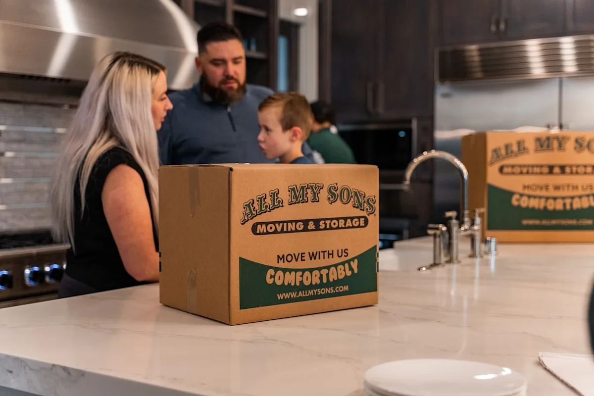 Professional packers from All My Sons Moving and Storage prepare to pack kitchen dishes for a family moving homes.