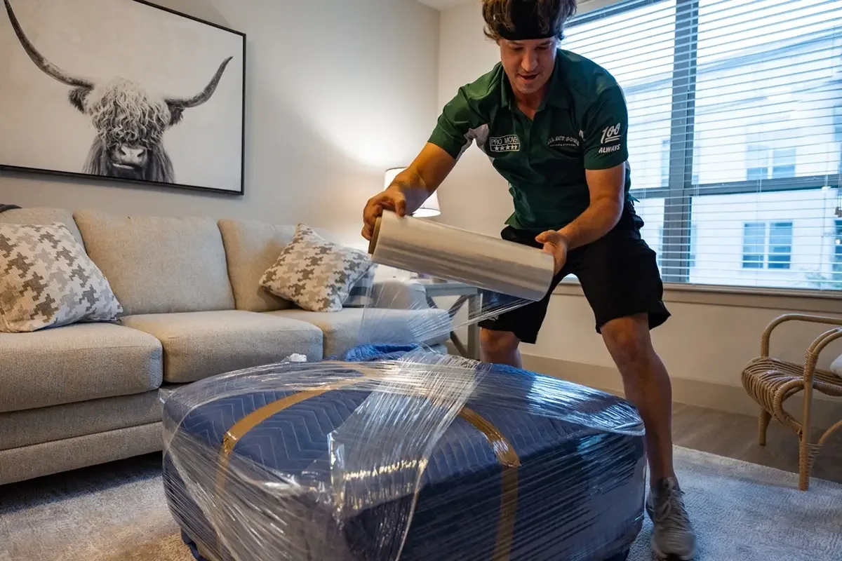 All My Sons team member wraps an ottoman to get it ready for long-term storage.