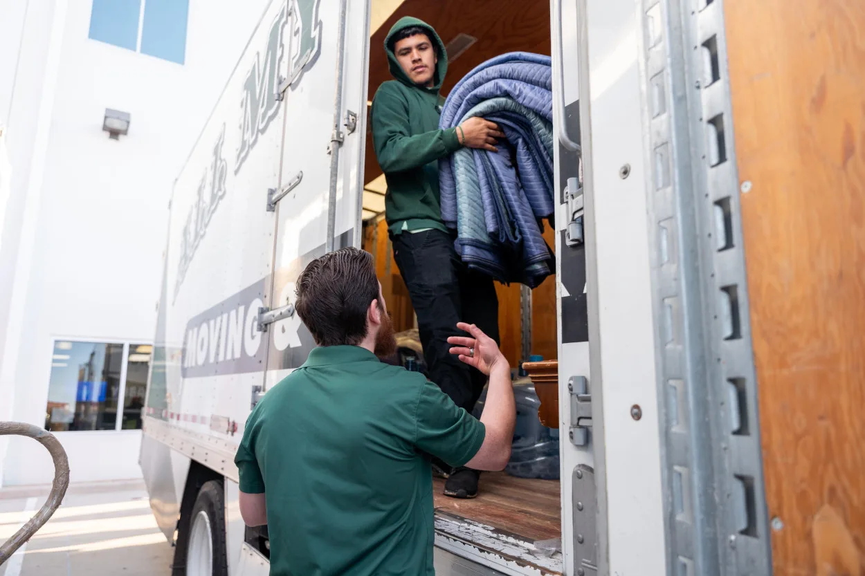 Professional packers from All My Sons Moving and Storage prepare furniture blankets for a move.