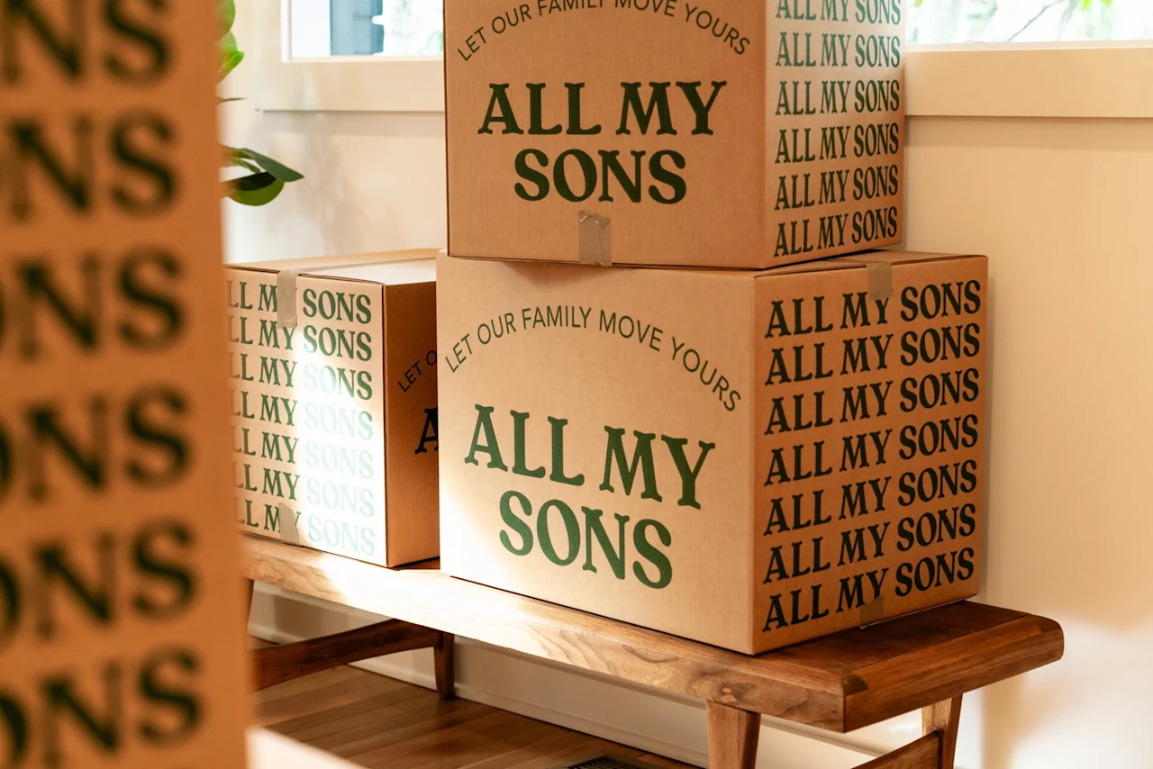 A pair of All My Sons moving boxes sits on a bench awaiting apartment movers. 